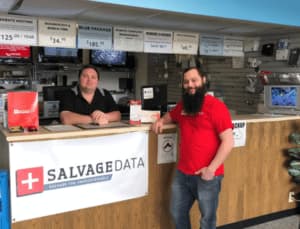 A man in a red shirt stands in front of a sign for Salvage Data.