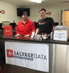 Two men standing in front of a sign that says Salvage Data.