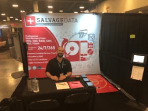 A man is sitting at a table in front of a large red and white banner.