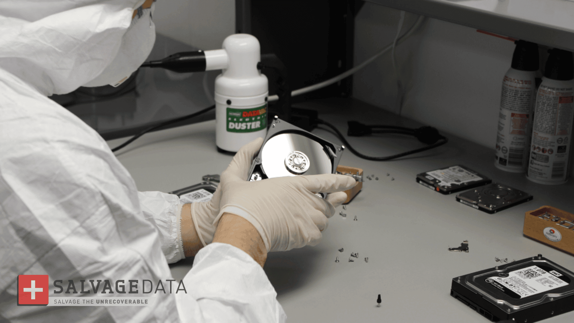 cleanroom technician repairing a hard drive under a laminar flow hood